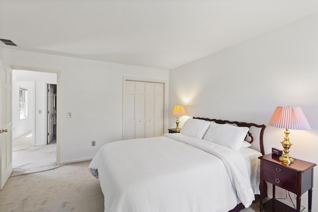 bedroom with baseboards, light carpet, a closet, and visible vents