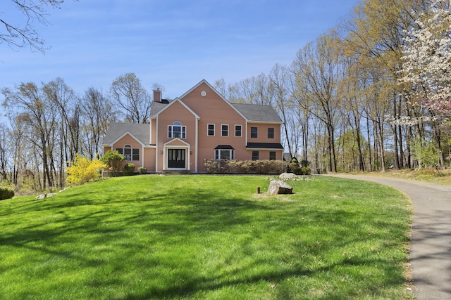 traditional-style home with a chimney and a front lawn