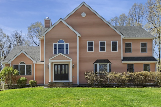 view of front of home with a front yard, french doors, a chimney, a shingled roof, and entry steps