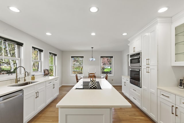kitchen featuring light wood-style floors, a sink, appliances with stainless steel finishes, and a kitchen island