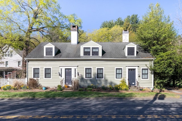 cape cod house featuring a chimney and entry steps