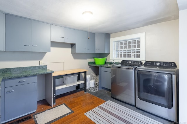 laundry room with a sink, dark wood-style flooring, cabinet space, and washer and clothes dryer