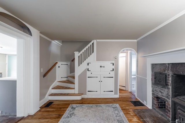 stairs featuring arched walkways, ornamental molding, baseboards, and wood finished floors