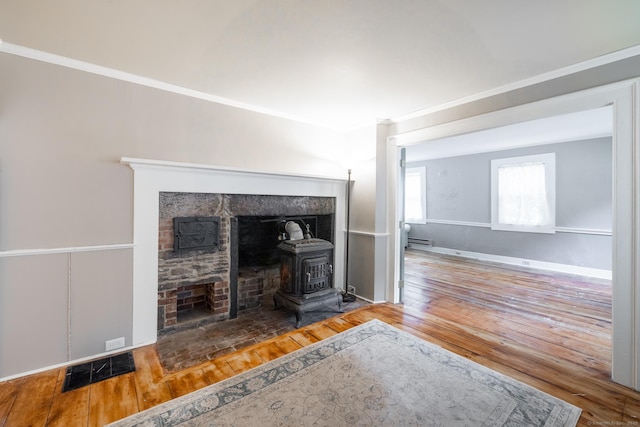 living area featuring visible vents, a wood stove, wood finished floors, and ornamental molding