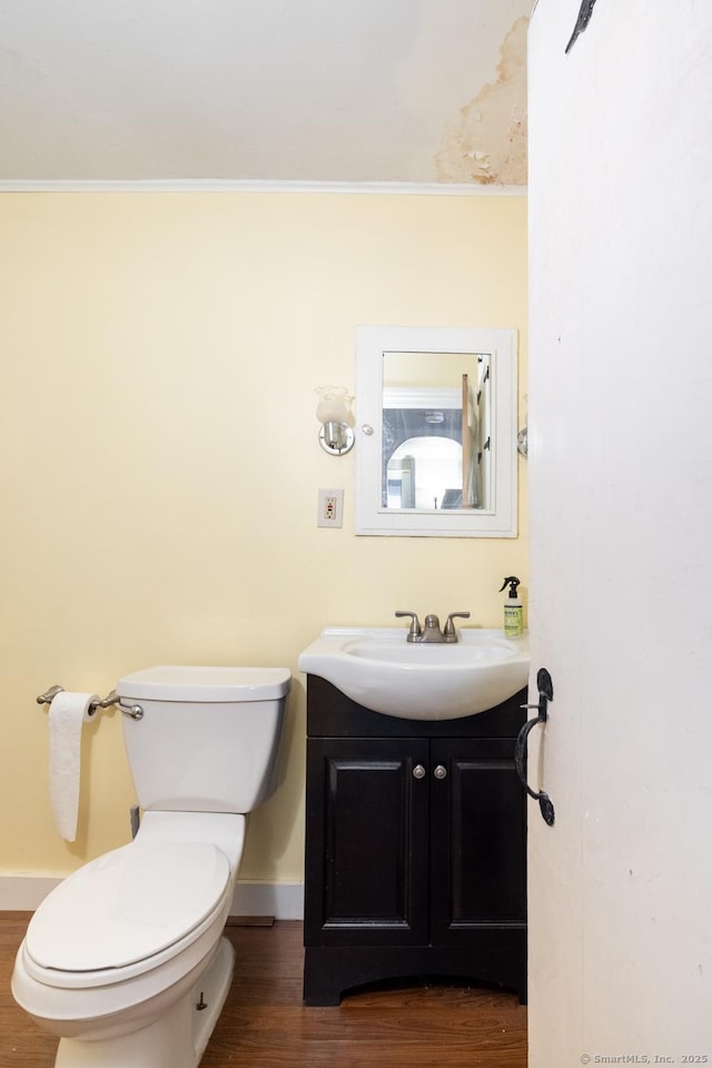 bathroom featuring crown molding, vanity, toilet, baseboards, and wood finished floors