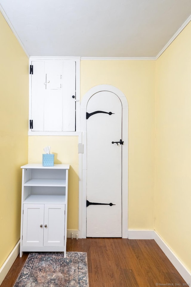 interior space with baseboards, ornamental molding, and wood finished floors