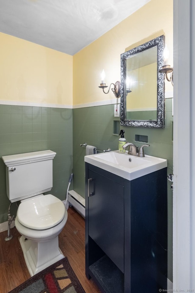 bathroom featuring vanity, wood finished floors, toilet, tile walls, and baseboard heating