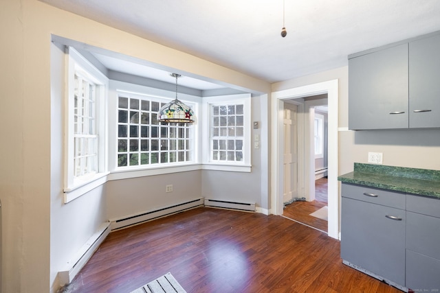 unfurnished dining area with dark wood-style flooring, baseboards, baseboard heating, and a baseboard radiator