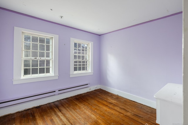empty room with baseboards, wood finished floors, and baseboard heating