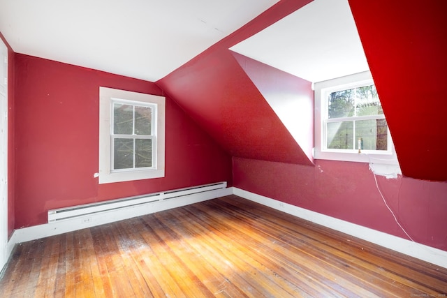 additional living space with baseboards, wood-type flooring, lofted ceiling, and baseboard heating