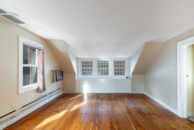 bonus room featuring visible vents, hardwood / wood-style floors, baseboard heating, an AC wall unit, and vaulted ceiling