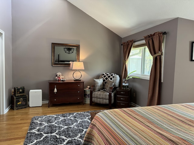 bedroom with baseboards, wood finished floors, and lofted ceiling