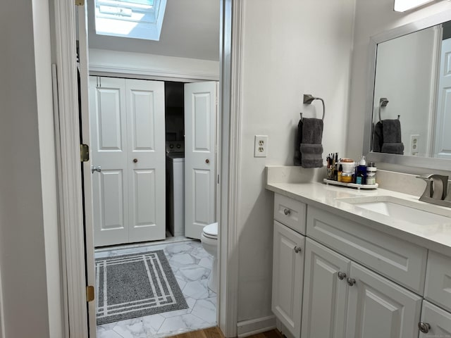 bathroom featuring toilet, washer / clothes dryer, vanity, and a skylight