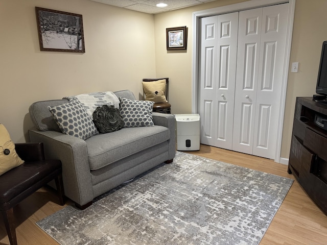 living room with a drop ceiling and light wood finished floors