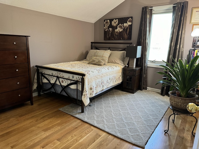 bedroom featuring light wood-style flooring and lofted ceiling