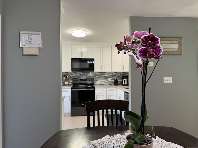 kitchen featuring backsplash, black microwave, white cabinets, and electric stove