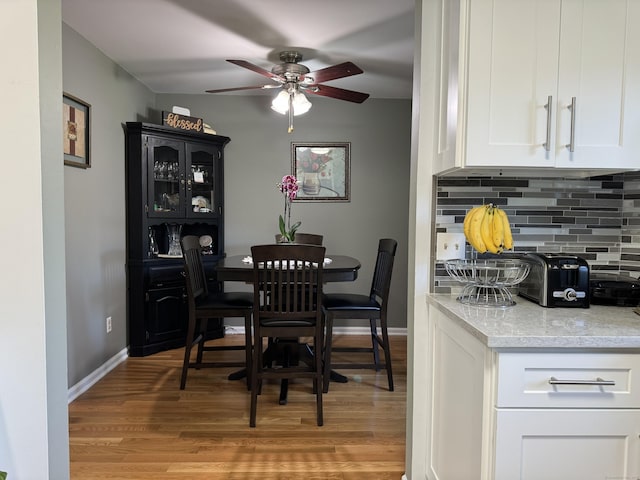 dining room featuring light wood-type flooring, baseboards, and ceiling fan