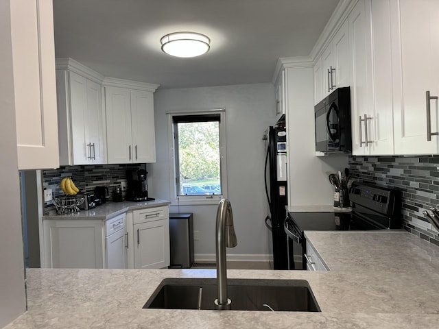 kitchen featuring backsplash, light countertops, black appliances, and a sink
