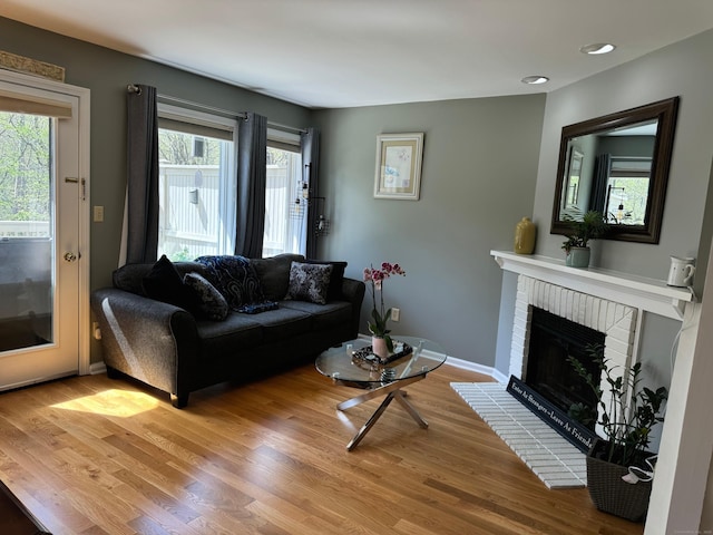 living area featuring baseboards, a fireplace, recessed lighting, and wood finished floors