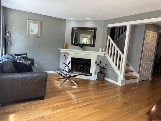 living area with baseboards, stairway, a fireplace, and light wood-style flooring