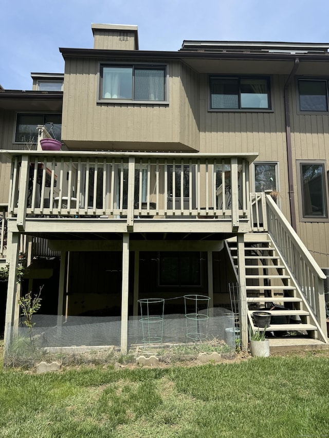 rear view of property with a lawn, a patio area, a wooden deck, and stairs
