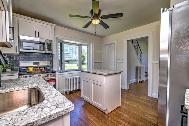 53 Bina Ave, Windsor, CT 06095 - kitchen featuring radiator heating unit, appliances with stainless steel finishes, dark wood-style floors, backsplash, and a ceiling fan