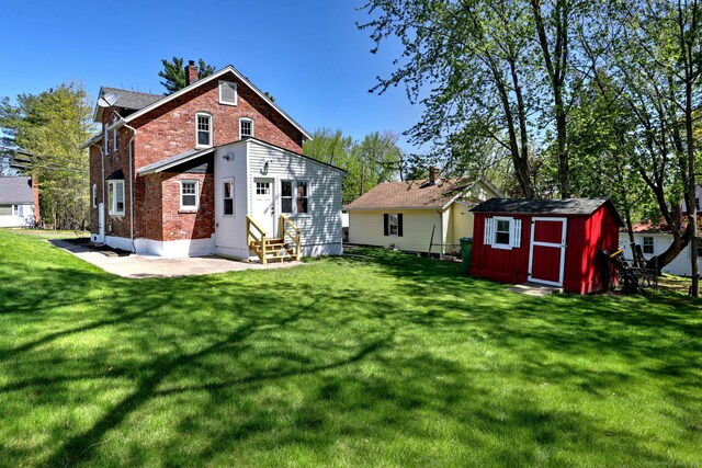 53 Bina Ave, Windsor, CT 06095 - back of house with entry steps, brick siding, a chimney, a lawn, and a storage shed