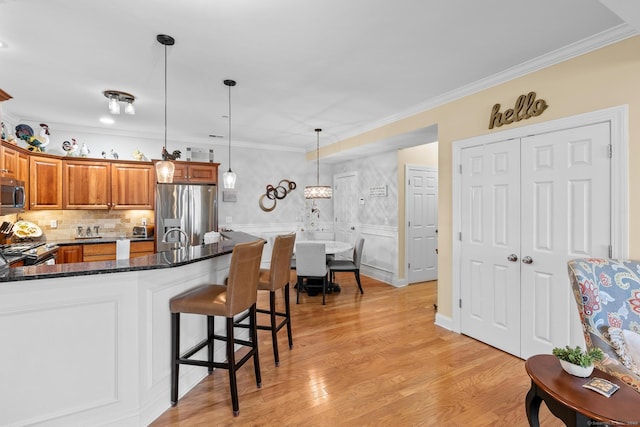95 S Ridge Ln Unit G103, Berlin, CT 06037 - kitchen with a kitchen breakfast bar, dark stone counters, brown cabinets, decorative light fixtures, and appliances with stainless steel finishes