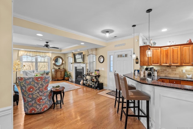 95 S Ridge Ln Unit G103, Berlin, CT 06037 - kitchen with dark stone countertops, backsplash, brown cabinetry, a kitchen bar, and light wood-style flooring
