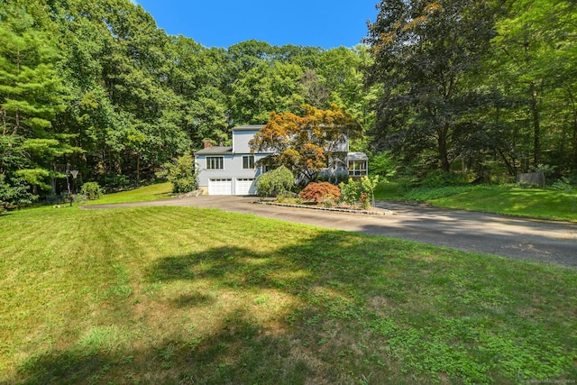 8 Oak Ln, Weston, CT 06883 - view of front facade featuring an attached garage, a front lawn, driveway, and a view of trees
