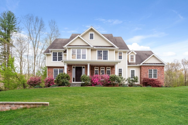 craftsman-style house featuring covered porch, brick siding, and a front yard