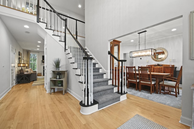 stairs featuring baseboards, recessed lighting, a towering ceiling, and wood finished floors