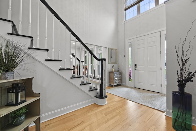 foyer featuring stairway, wood finished floors, baseboards, and a high ceiling