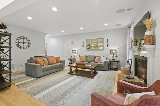 living area with recessed lighting, wood finished floors, baseboards, and a glass covered fireplace