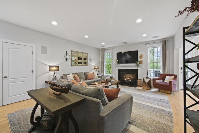 living room featuring recessed lighting, a fireplace with flush hearth, and light wood-type flooring