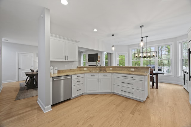 kitchen with a peninsula, a sink, white cabinetry, decorative light fixtures, and dishwasher