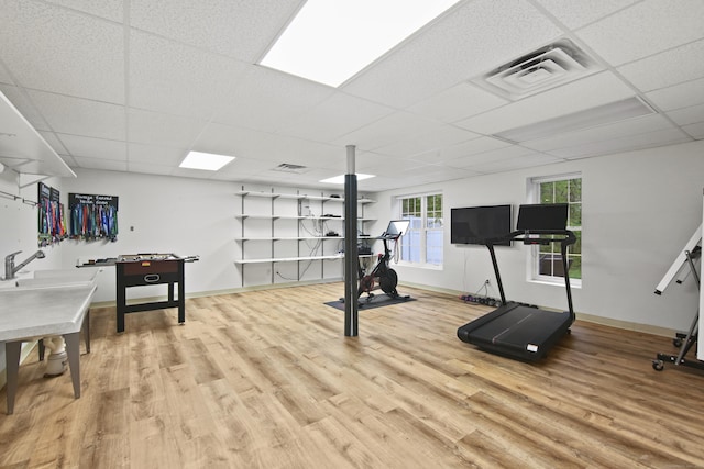 workout area with a paneled ceiling, baseboards, visible vents, and wood finished floors