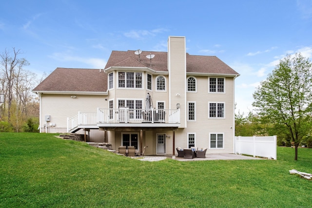 rear view of house featuring an outdoor living space, a chimney, a lawn, a patio area, and a wooden deck