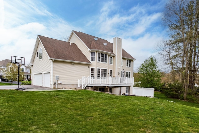 back of property with a chimney, a lawn, a garage, concrete driveway, and roof with shingles