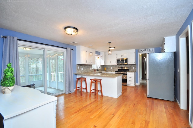 187 Hollister Dr, Avon, CT 06001 - kitchen featuring stainless steel appliances, a sink, a peninsula, light wood-style flooring, and white cabinetry