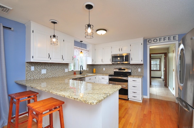 187 Hollister Dr, Avon, CT 06001 - kitchen featuring stainless steel appliances, a peninsula, a sink, visible vents, and decorative backsplash