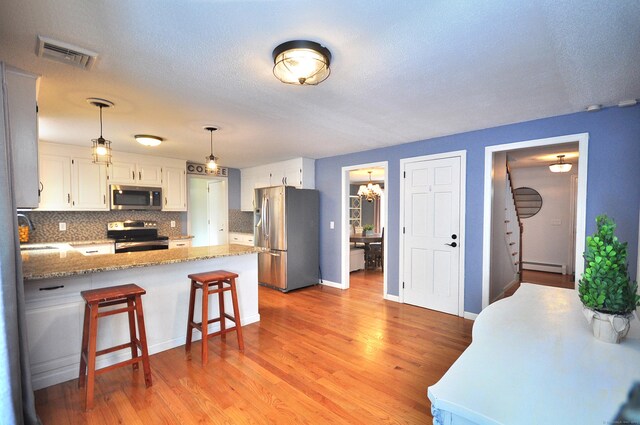 187 Hollister Dr, Avon, CT 06001 - kitchen featuring a baseboard radiator, decorative backsplash, stainless steel appliances, a peninsula, and visible vents