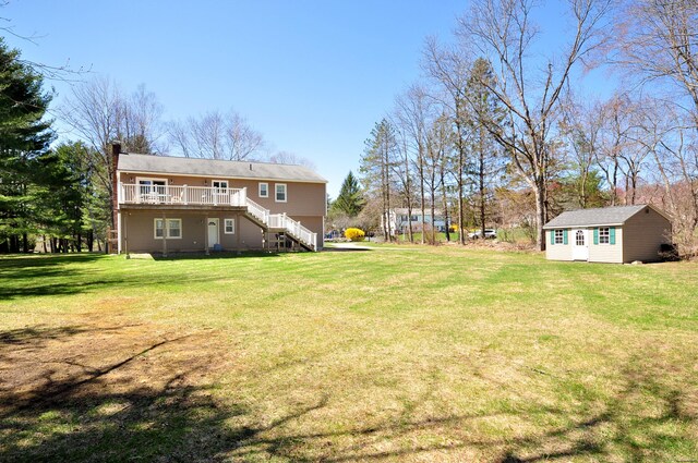 view of yard featuring stairway, a wooden deck, and an outbuilding