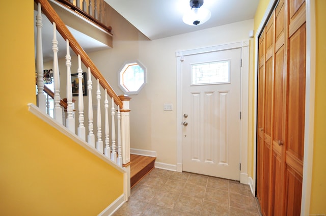 foyer with baseboards, stairway, and light tile patterned floors