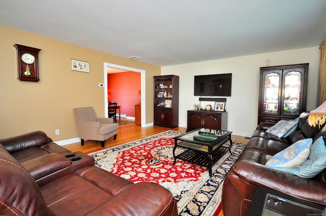 living area featuring baseboards, visible vents, and wood finished floors