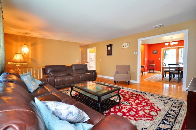 living area with a notable chandelier, visible vents, baseboards, baseboard heating, and wood finished floors
