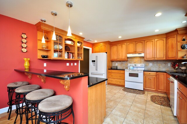 kitchen with under cabinet range hood, a kitchen bar, open shelves, a peninsula, and white appliances