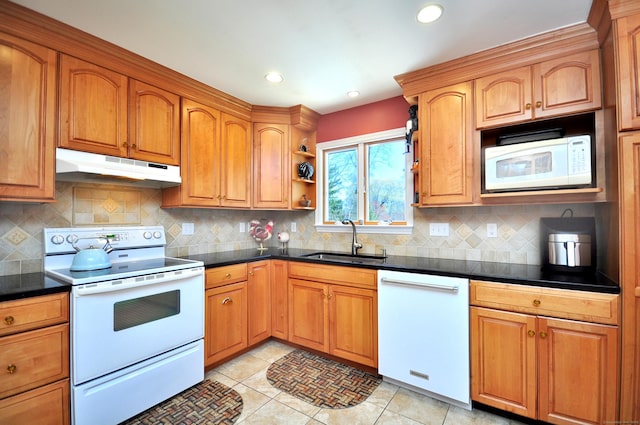 kitchen with a sink, dark countertops, white appliances, and under cabinet range hood