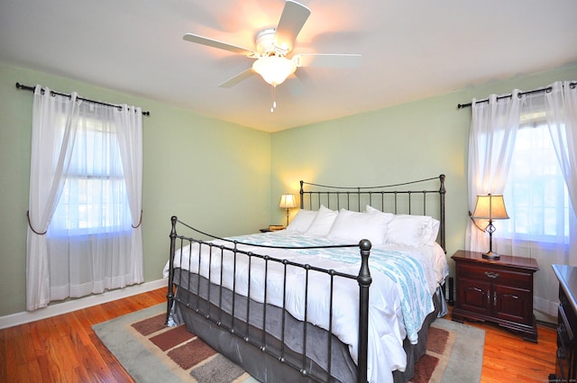 bedroom featuring baseboards, wood finished floors, and a ceiling fan
