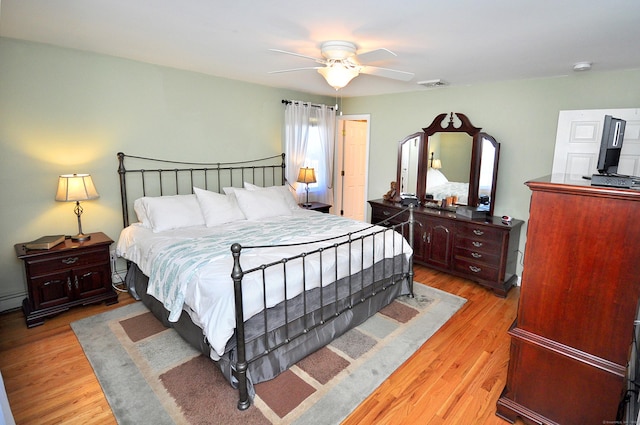 bedroom with light wood finished floors, a ceiling fan, and visible vents